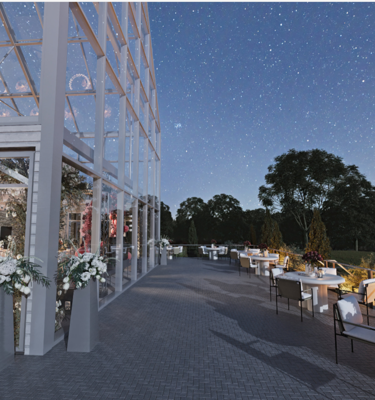 An elegantly lit outdoor dining space beside a glass-walled building under a starry sky, with tables and decorative flower arrangements.