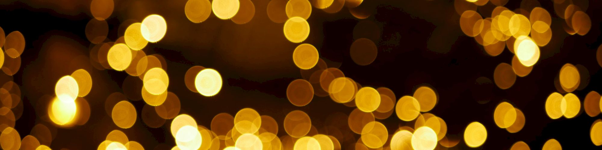 The image shows a bokeh effect with warm golden-yellow lights, creating a festive and blurred glowing ambiance against a dark background.